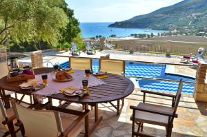 a wooden table and chairs on a patio with a pool at Villa Tireda in Keri