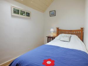 Ty Gwyn في Goodwick: غرفة نوم بسرير ازرق وعليها وردة حمراء