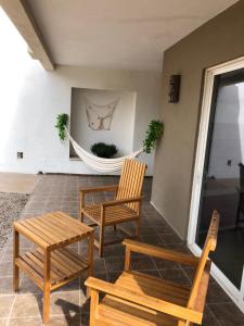 porche con 2 sillas, mesa y hamaca en Caracoles Homes, en Puerto Peñasco