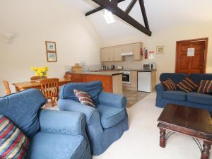 ein Wohnzimmer mit 2 blauen Sofas und einer Küche in der Unterkunft Holly Berry in Wood Norton