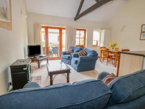ein Wohnzimmer mit blauen Sofas und einem TV in der Unterkunft Holly Berry in Wood Norton
