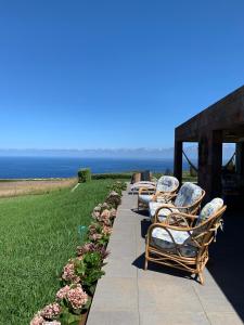 une rangée de chaises assises à côté de l'océan dans l'établissement Villa Mariense, à Vila do Porto