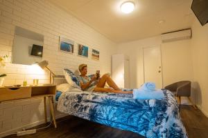 a woman sitting on a bed in a room at Nomads Noosa in Noosa Heads