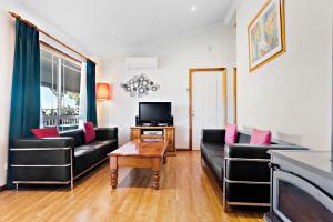 a living room with two black couches and a tv at Cottages on Lovedale - Cottage No. 1 in Lovedale