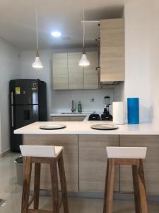 een keuken met 2 krukken en een zwarte koelkast bij NUEVO PRECIOSO APARTAMENTO in Cartagena
