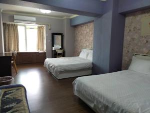 a hotel room with two beds and a window at Grapefruit Heping Guesthouse in Hualien City