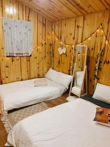 two beds in a room with wooden walls at EUDORA HOUSE 2 in Da Thien