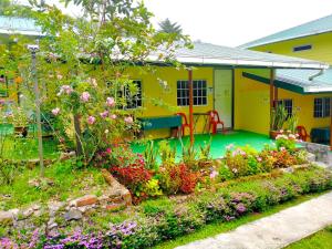 a garden in front of a yellow house with flowers at Soboroong Farmer's Cottage in Kundasang