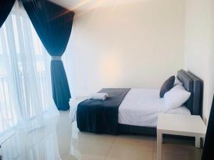 a bedroom with a bed and a blue curtain at Yamada Residence, Trefoil in Setia Alam