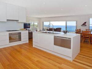 a kitchen with white cabinets and a view of the ocean at Aqua in Kiama Downs