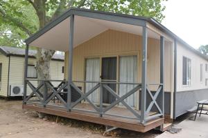 une terrasse couverte sur une petite maison dans l'établissement Ball Park Caravan Park, à Corowa
