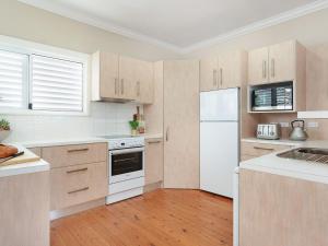 a kitchen with white appliances and wooden cabinets at The Old Bottleshop in Currarong