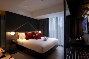 a bedroom with a large bed with red pillows at Awann Sewu Boutique Hotel and Suite Semarang in Semarang