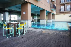 a table and chairs next to a swimming pool at Comfy & Well Appointed 2BR at Tamansari Panoramic Apartment By Travelio in Bandung
