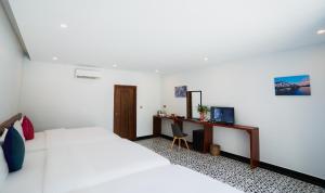a white bedroom with a bed and a desk at Kampot Sweet Boutique in Kampot
