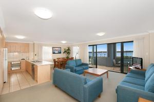 sala de estar con 2 sofás azules y cocina en Sandcastles On The Broadwater, en Gold Coast