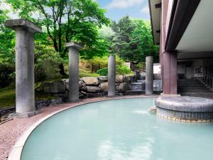 a swimming pool with a fountain in a garden at Dai-ichi Takimotokan in Noboribetsu