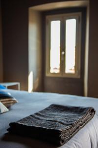 Una toalla puesta en una cama con ventana en Boutique Hotel Al Palazzo Rosso, en Neive