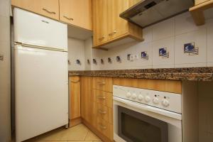 cocina con nevera blanca y fogones en Rentalmar Gavina d'Or Apartamentos, en Miami Platja