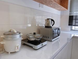 uma cozinha com um micro-ondas e uma batedeira no balcão em Desaru KTV Natural wood style by Joyfully 31A7 em Desaru