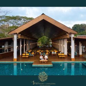 zwei Personen sitzen in einem Pavillon neben einem Pool in der Unterkunft Symphony Samudra Beachside Jungle Resort And Spa in Port Blair