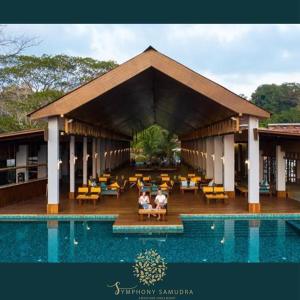two people sitting in a pavilion next to a swimming pool at Symphony Samudra Beachside Jungle Resort And Spa in Port Blair