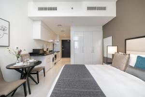 a bedroom with a bed and a table and a kitchen at HiGuests - Elegant Studio with Pool and Private Balcony in Dubai