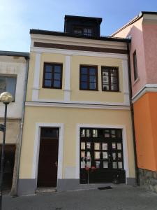 um edifício amarelo com portas e janelas pretas em Apartmán U Hradeb Tachov em Tachov