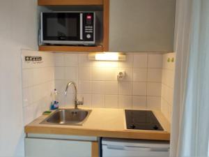 eine Küche mit einer Spüle und einer Mikrowelle in der Unterkunft StudioLille - Gambetta in Lille