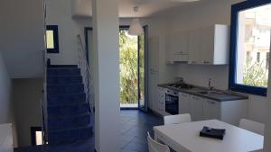 a kitchen with a staircase and a white table and chairs at Galatea House in Marinella di Selinunte