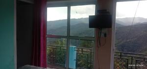 a bedroom with a window with a view of mountains at Golok Homestay in Salyāna +7 photos