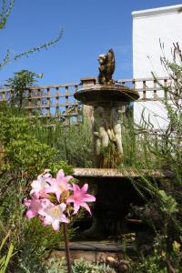 a fountain in a garden with pink flowers at Fynbos Ridge Country House & Cottages in Plettenberg Bay