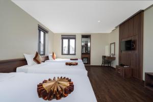 a hotel room with two beds and a television at Boston Halong Hotel in Ha Long