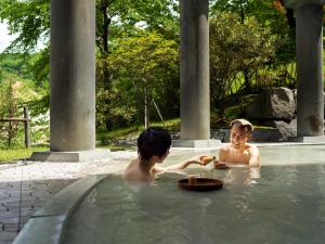 two boys in a hot tub in a swimming pool at Dai-ichi Takimotokan in Noboribetsu