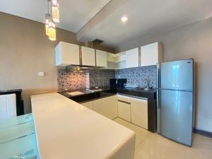 a kitchen with white cabinets and a stainless steel refrigerator at Deluxe & Well Appointed 2BR at El Royale Apartment By Travelio in Bandung