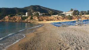 uma praia com espreguiçadeiras azuis e água em playa mar 2 em L'Alfàs del Pi