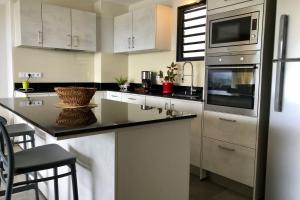a kitchen with white cabinets and a black counter top at Alicia's Sky flat on the heights with nice view on the sea and Papeete in Papeete