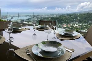 a table with wine glasses and plates on it at Alicia's Sky flat on the heights with nice view on the sea and Papeete in Papeete