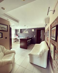 a living room with a white couch and a kitchen at Apartment Klet in Sisak