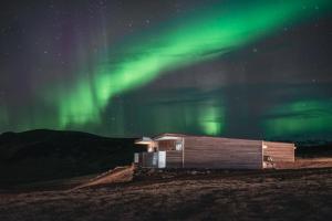 a building under the northern lights in a field at Black Beach Suites in Vík
