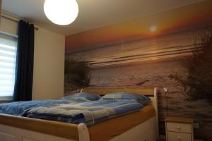 ein Schlafzimmer mit einem Bett und einem Gemälde des Strandes in der Unterkunft MeerZeit-Sellin in Ostseebad Sellin