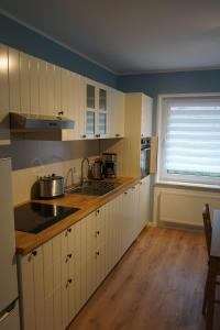 eine Küche mit weißen Schränken, einem Waschbecken und einem Fenster in der Unterkunft MeerZeit-Sellin in Ostseebad Sellin