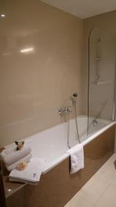 a bathroom with a tub and a shower with towels at Hotel Saffron in Bratislava