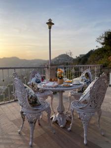 a table and chairs on a balcony with a view at Tree of Life Highlands Mussoorie in Mussoorie