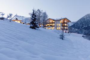 ein Haus auf einem schneebedeckten Hügel im Schnee in der Unterkunft Hotel Ritzlerhof - Adults only in Sautens