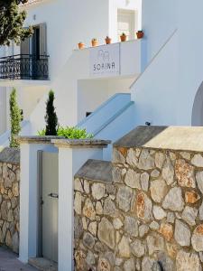 ein weißes Haus mit einer Steinmauer und einer Treppe in der Unterkunft SORINA Beloved Rooms in Spetses