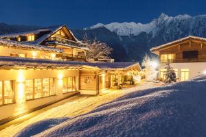 a chalet in the snow in the mountains at night at Hotel Ritzlerhof - Panorama und Spa in Sautens