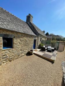 a stone house with a wooden deck next to a building at Le Courlis in Guimaëc