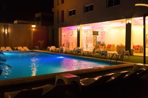 a swimming pool at night with chairs and a restaurant at Hotel du Golfe in Lomé