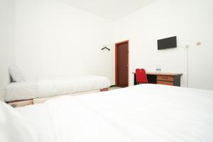 a bedroom with two beds and a desk and a chair at Merapi Inn Syariah by ecommerceloka in Surabaya
